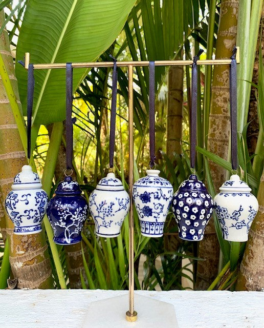 A collection of 6 mini blue and white ginger jars hanging from a stand outside.