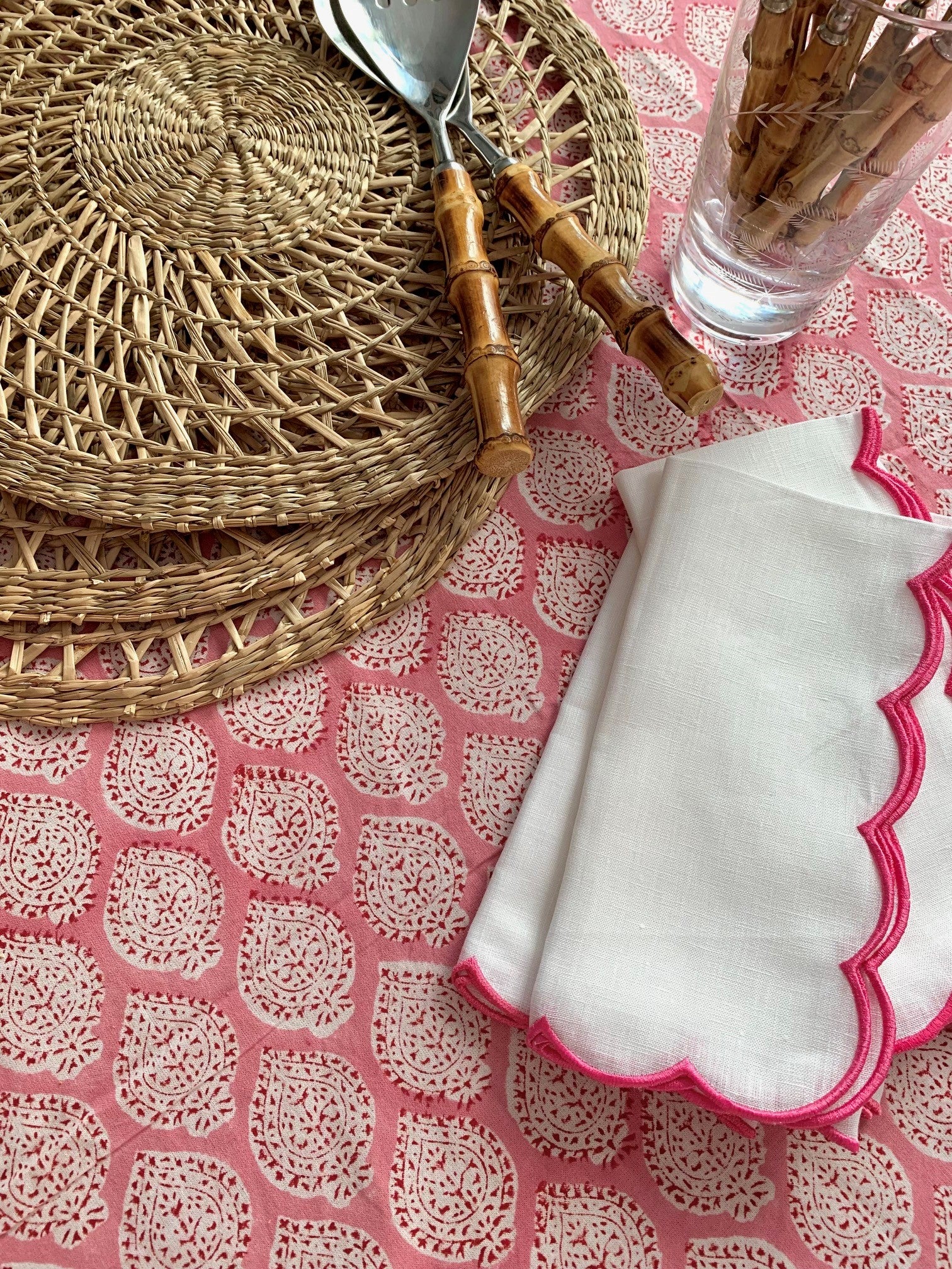 PInk block printed tablecloth with scallop edged linen napkins, raffia placemats and bamboo cutlery.