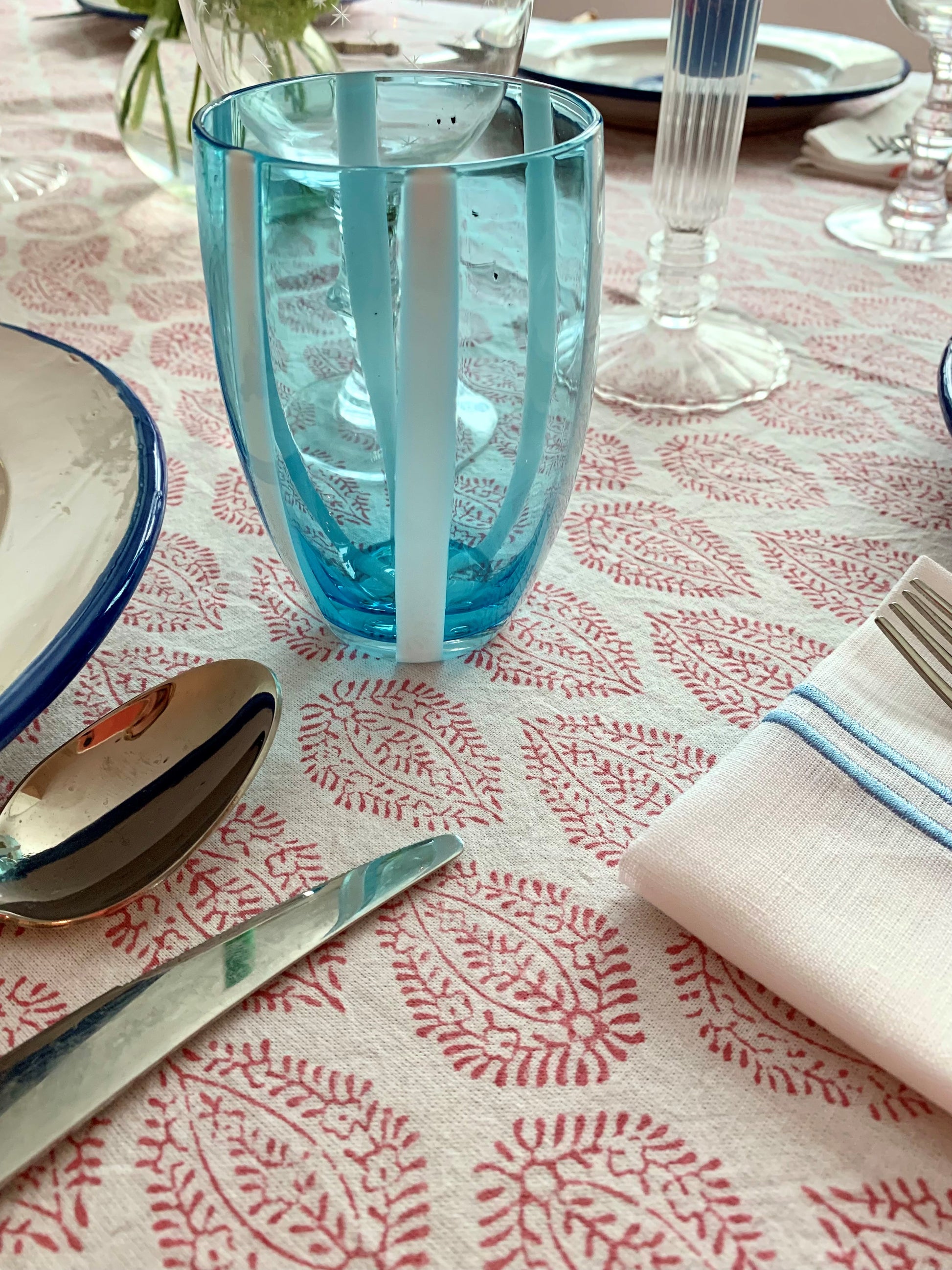 A close up of a blue tumbler on a block printed tablecloth.